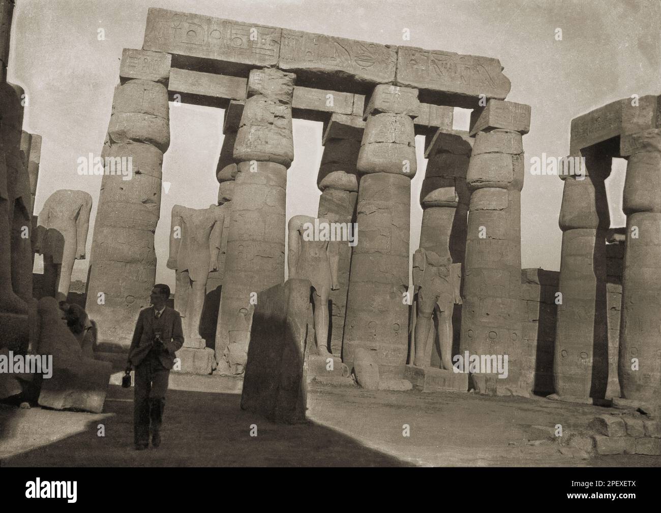 Intorno al 1930, storico, un gentiluomo che cammina nell'antico sito del Tempio di Karnak, Luxor, Egitto, un complesso di templi di colonne, obelischi, cartigli e statue risalenti all'inizio del II millennio a.C. Foto Stock