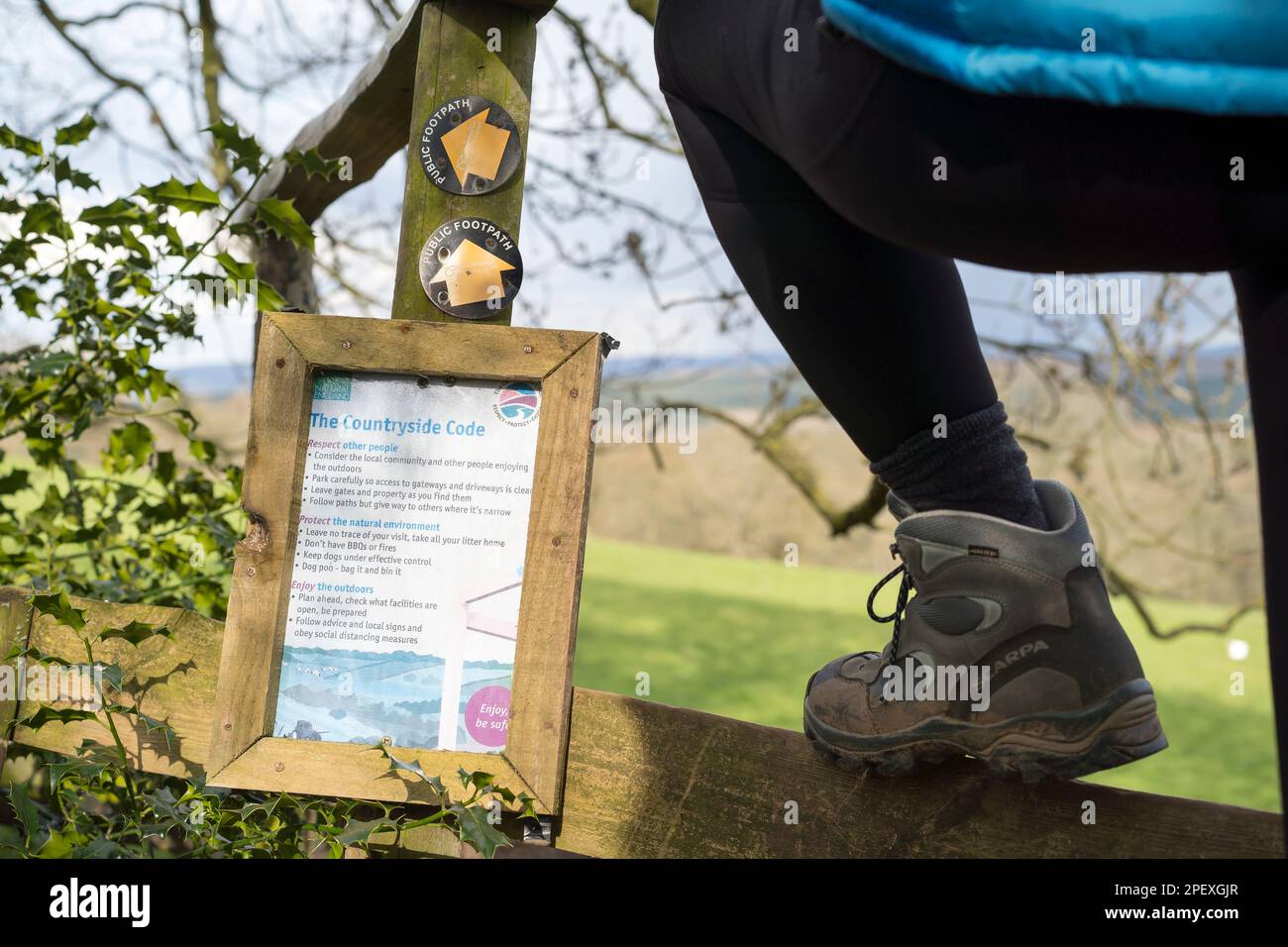 Il codice di campagna su un posto in campagna. Una donna escursionista sale sopra il paletto accanto al segno. Foto Stock