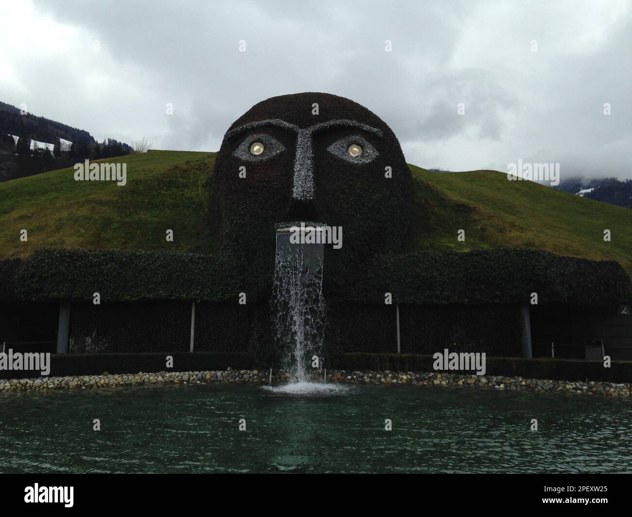 Una fontana di una grande scultura di una testa che sporge dalla superficie dell'acqua. Foto Stock