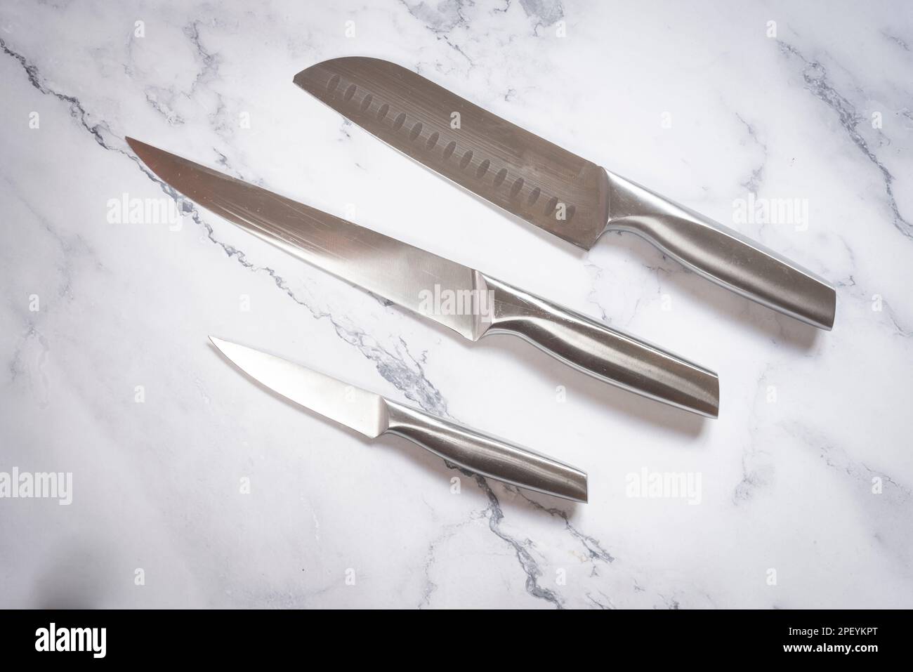 Set coltelli da cucina in acciaio su tavola in marmo. Foto Stock