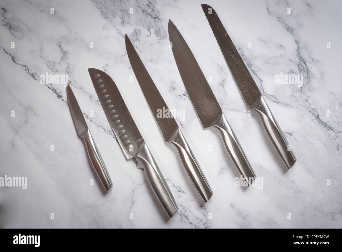 Set coltelli da cucina in acciaio su tavola in marmo. Foto Stock
