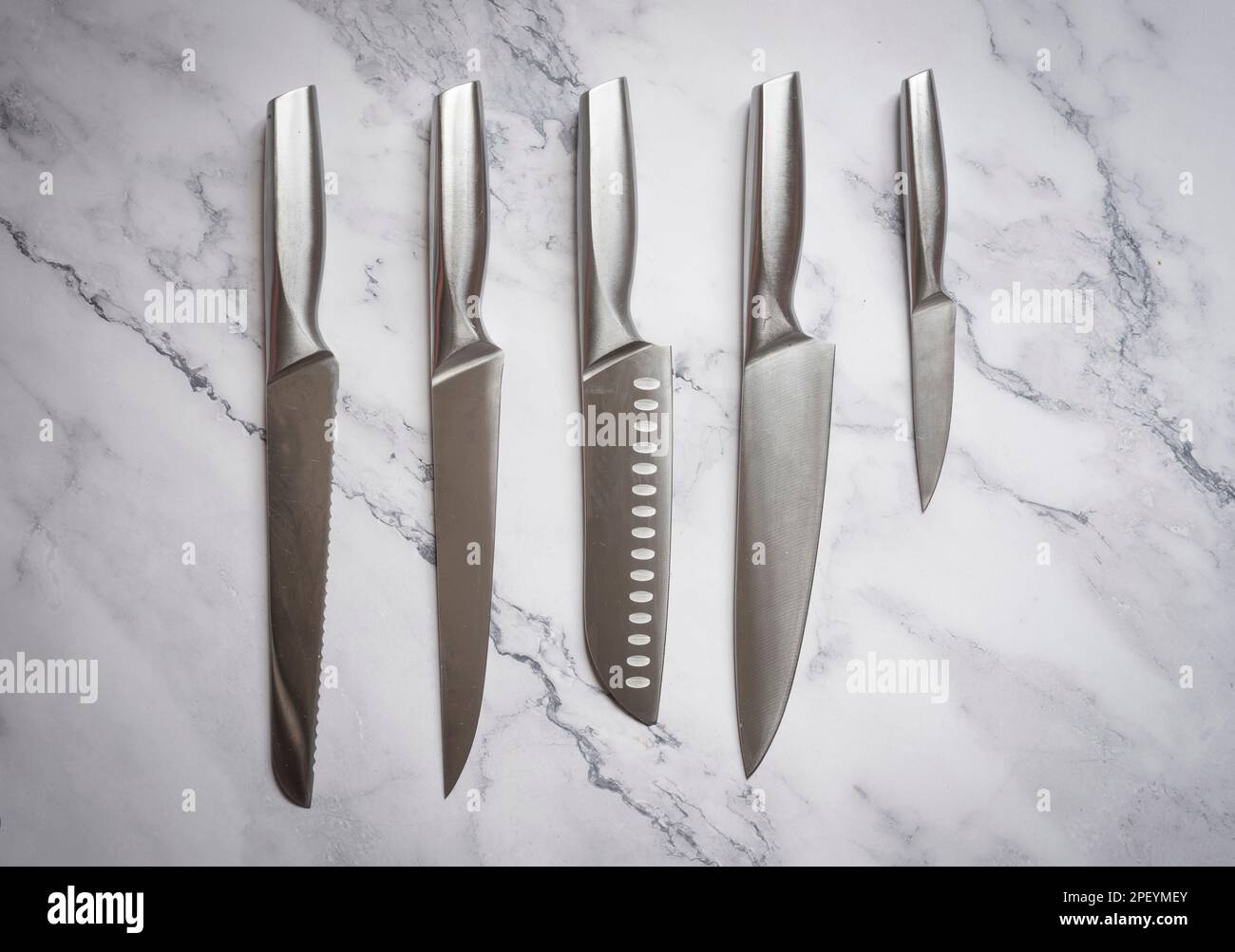 Set coltelli da cucina in acciaio su tavola in marmo. Foto Stock