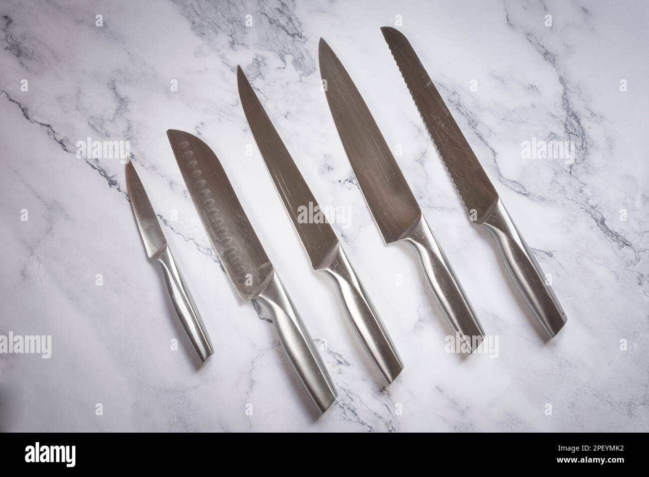 Set coltelli da cucina in acciaio su tavola in marmo. Foto Stock