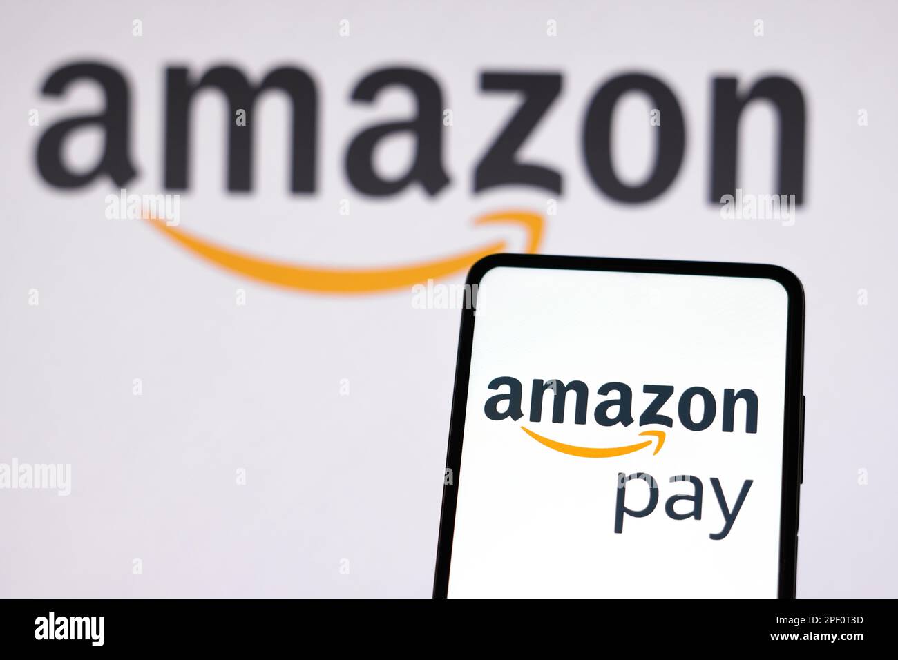 In questa immagine il logo Amazon Pay visualizzato sullo smartphone e sullo sfondo il logo Amazon. Foto Stock