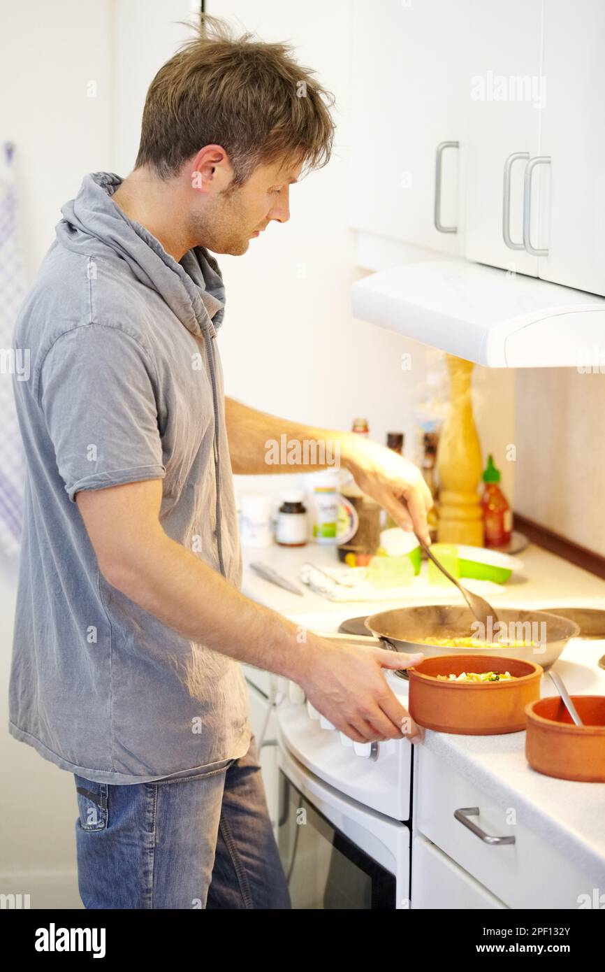 Serve un pasto sano fatto in casa. Vista laterale di un giovane ragazzo che sta mangiando hes appena preparato. Foto Stock