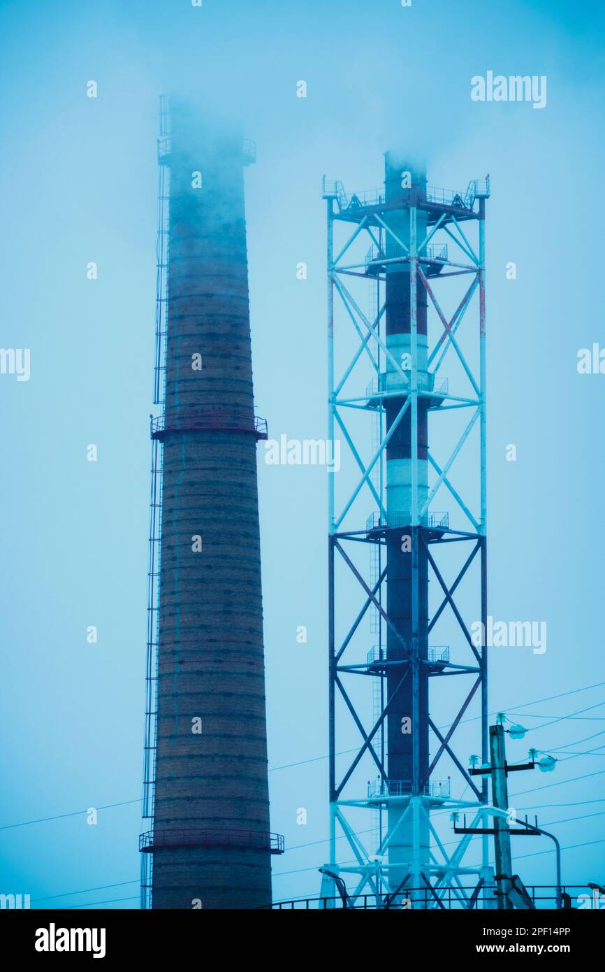 Due tubi industriali fumano inquinando l'ambiente con gas nocivi Foto Stock