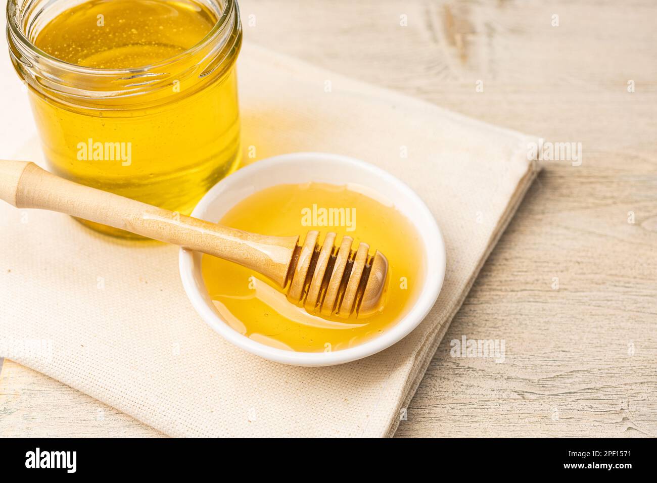 Ape di miele in vaso di vetro e ciotola con fiore di tiglio con cucchiaia di miele su fondo di legno. Prodotti di api. Concetto di cibo biologico sano. Vista dall'alto Foto Stock