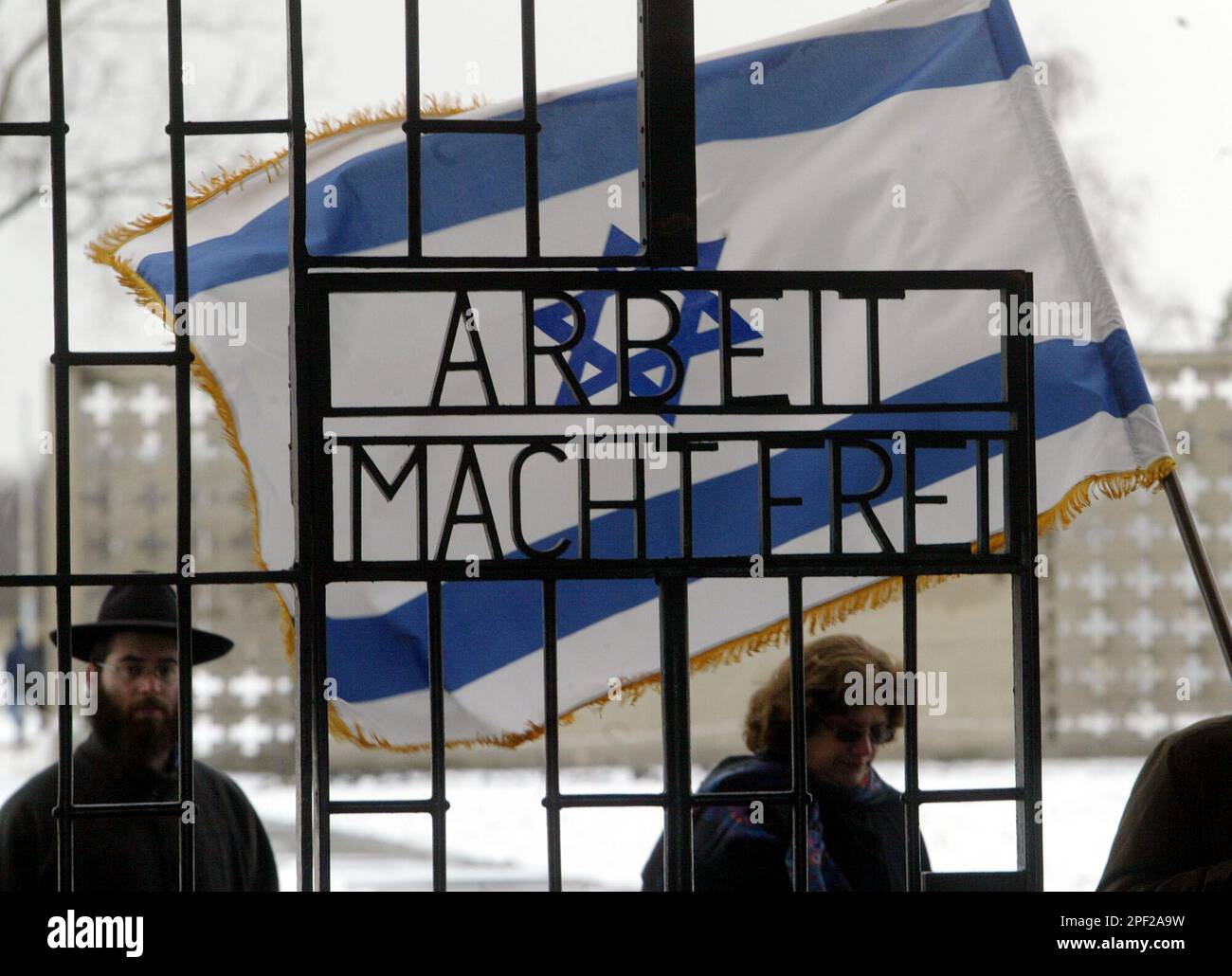 Members of Berlin's Jewish community walk with an Israeli Flag behind the entrance gate of the former Nazi concentration camp Sachsenhausen prior to a visit of Lieutenant-General Moshe Ya'alon, Israel Defense Force ( IDF ) Chief-of-Staff, at the memorial near Oranienburg, 50 kilometres north of Berlin on Wednesday, Feb. 11, 2004. (AP Photo/Markus Schreiber) Foto Stock