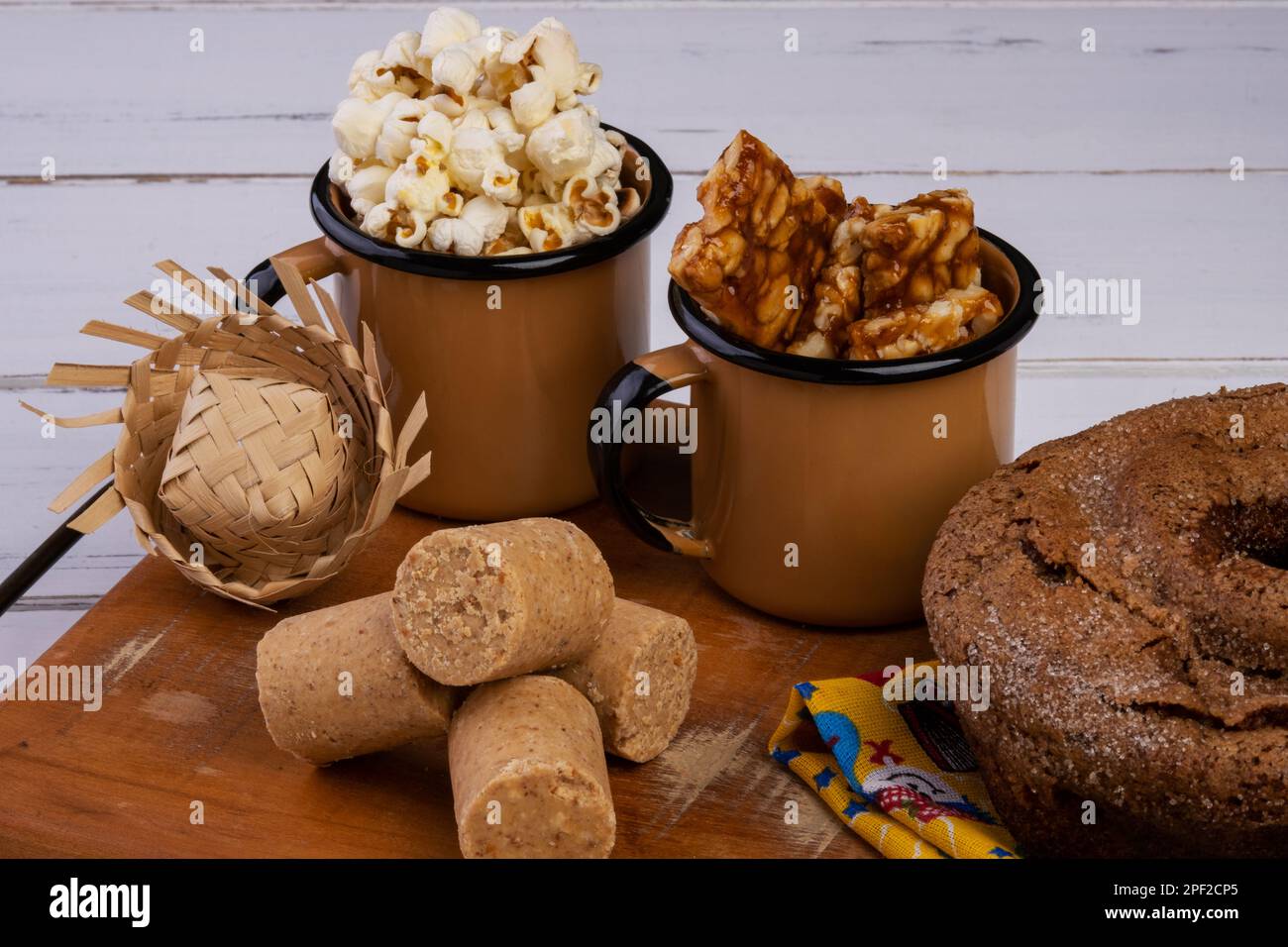 Vassoio di legno con torta, popcorn, pachochinha e pé de moleque - festa di giugno. Foto Stock