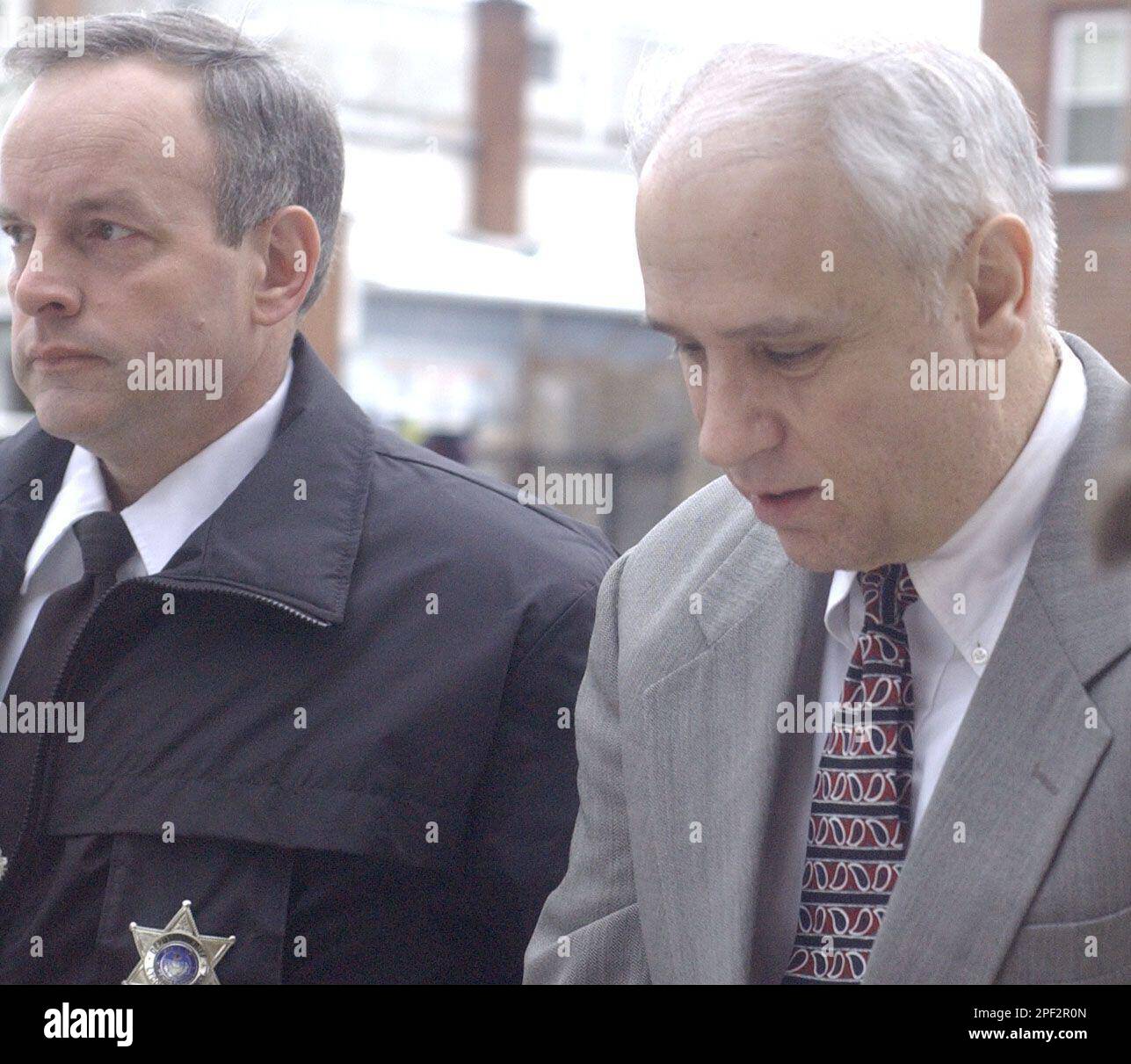 A County sheriff's deputy leads Dr. Richard W. Illes, Sr. into the County