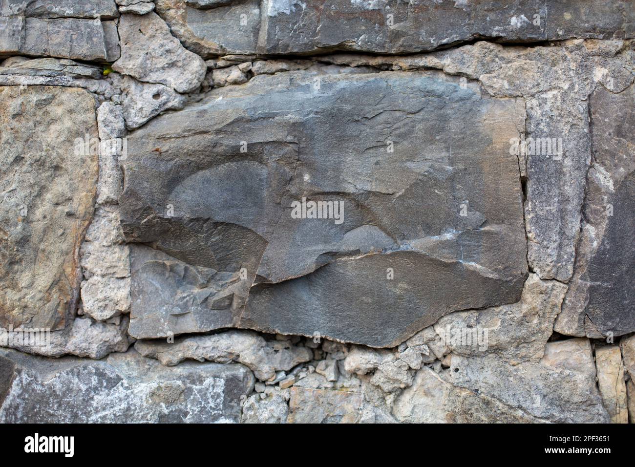 La grande pietra è saldamente incorporata nel muro, aggiungendo forza e stabilità alla struttura Foto Stock