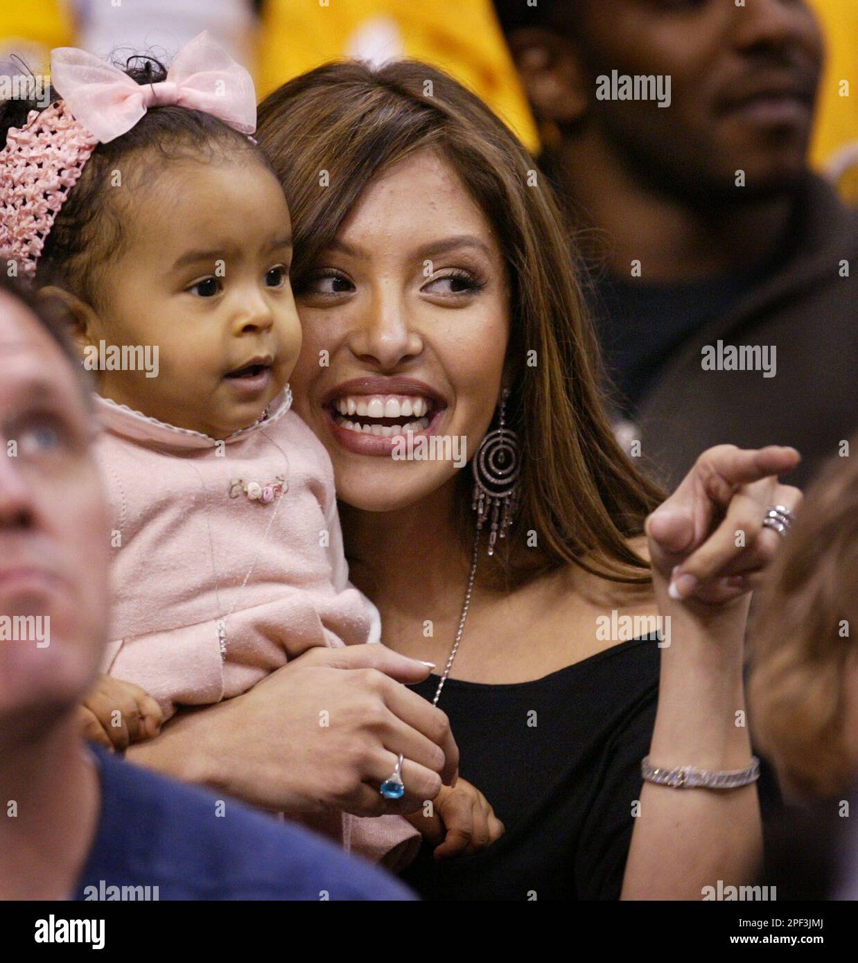 Vanessa Bryant, wife of Los Angeles Lakers' Kobe Bryant, holds their daughter Natalia as she points to Bryant during the Lakers' game with the San Antonio Spurs in Los Angeles on Friday, Nov. 28, 2003. (AP Photo/Chris Carlson) Foto Stock