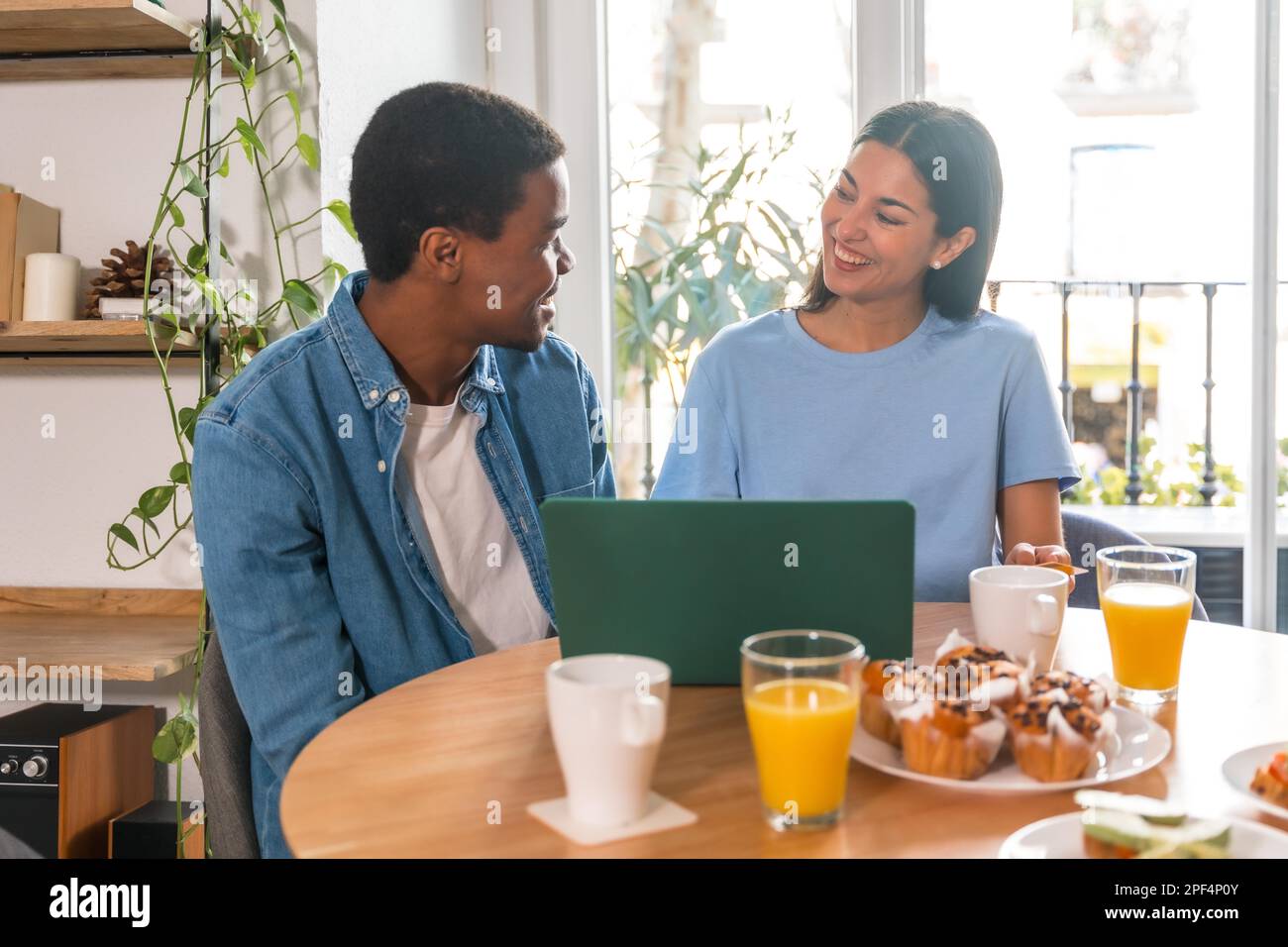 Coppia multietnica che effettua l'acquisto online con il computer mentre fa colazione Foto Stock