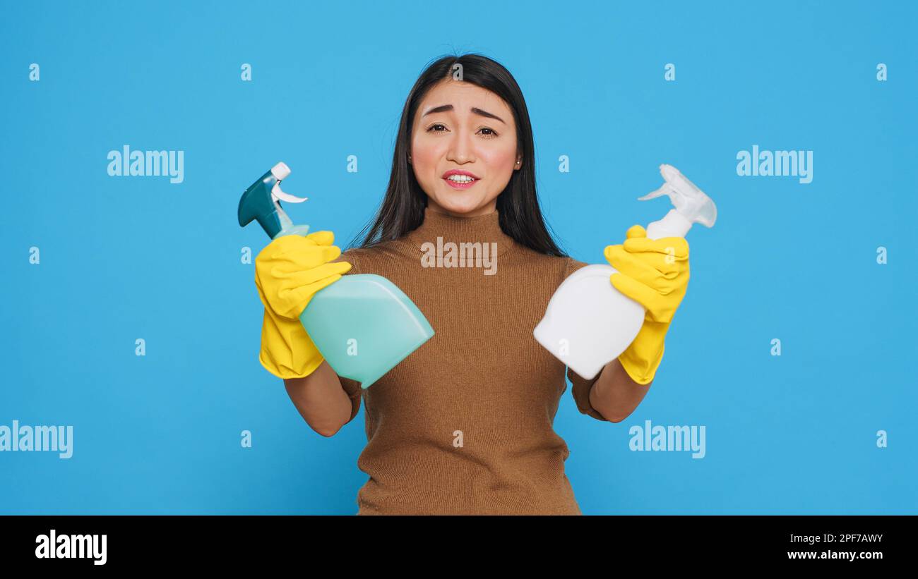 Detergente per la casa allegro indossando guanti di gomma gialla mentre si mostra detergente spray chimico davanti alla fotocamera, promuovendo il prodotto di pulizia. Il housekepper professionale ha lavorato duro per effettuare una sede pulita Foto Stock