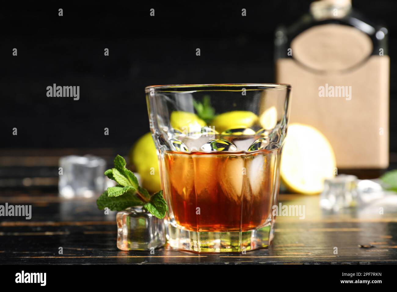 Bicchiere di rum con cubetti di ghiaccio su fondo di legno scuro Foto stock  - Alamy