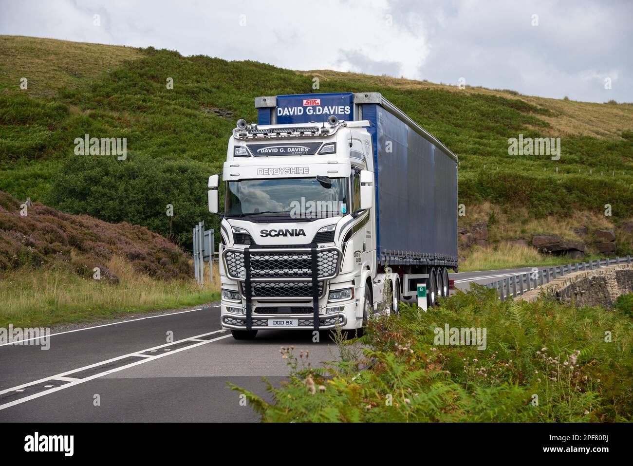 Scania Truck con rimorchio per il trasporto di marciapiede affronta una curva in discesa sul Woodhead Pass nello Yorkshire Foto Stock