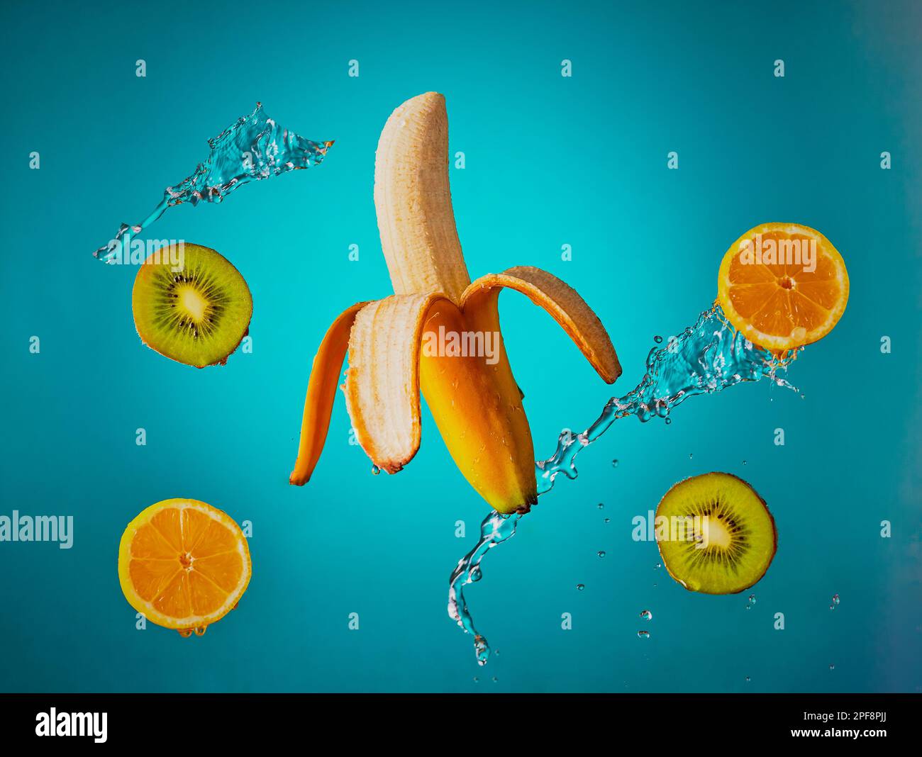 Frutta galleggiante con acqua spruzzata sopra di essa, sparata su sfondo blu sfumato. Foto Stock