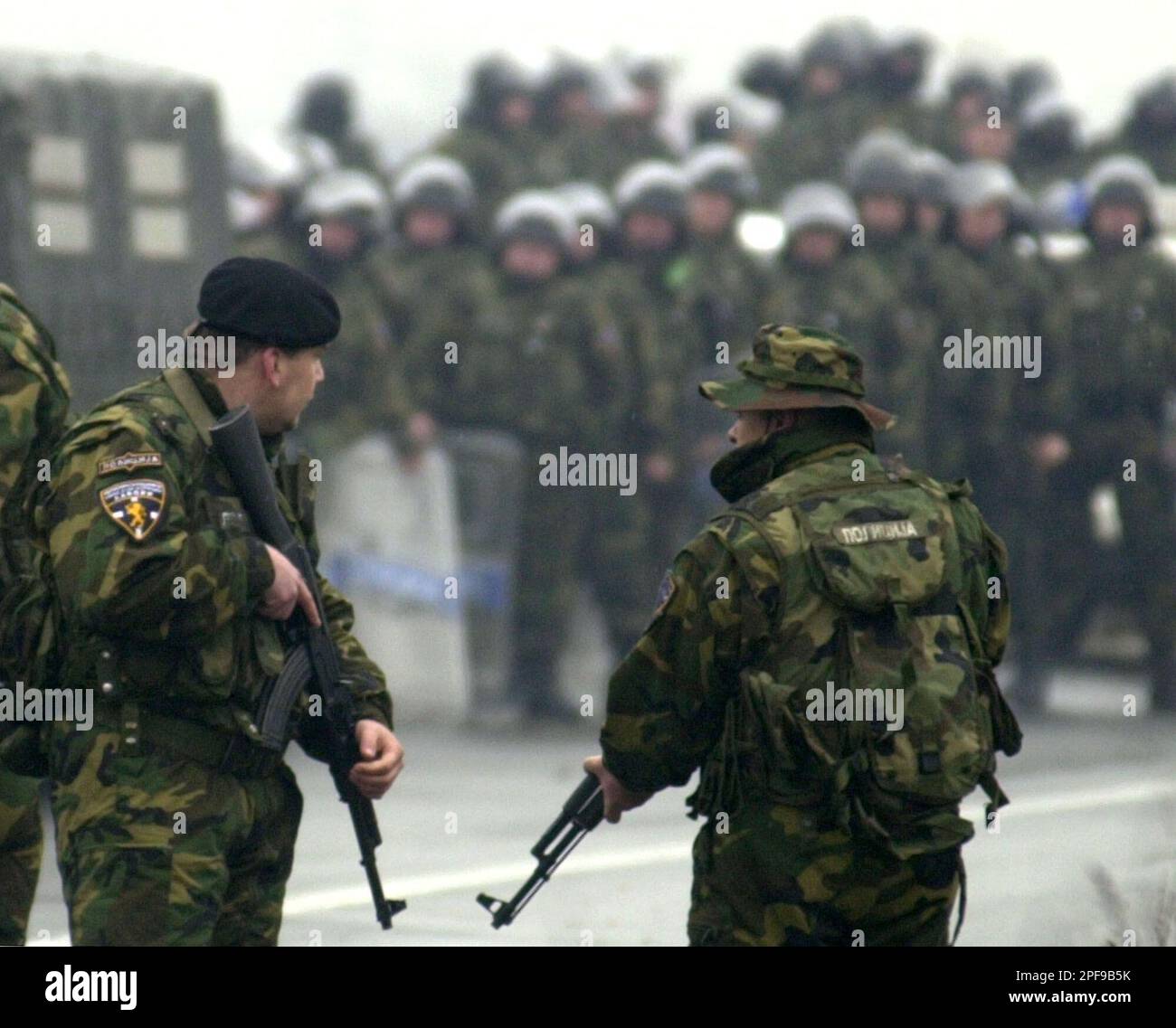 Members of the special Macedonia police unit "Lions", blocking the road near Stenkovec, 6 kms (4 miles) north of Macedonia's capital Skopje, Wednesday, Jan. 22, 2003, stand in front of riot police. Several hundreds members of the special police unit, who once fought Albanian rebels, blocked the road linking the capital with the Macedonia-Kosovo border, demanding the government immediately pay their wages and guarantee their jobs. After the Albanian insurgency ended with a western brokered peace-dealin August 2001, international officials demanded the unit be disbanded. (AP Photo/Boris Grdanosk Foto Stock