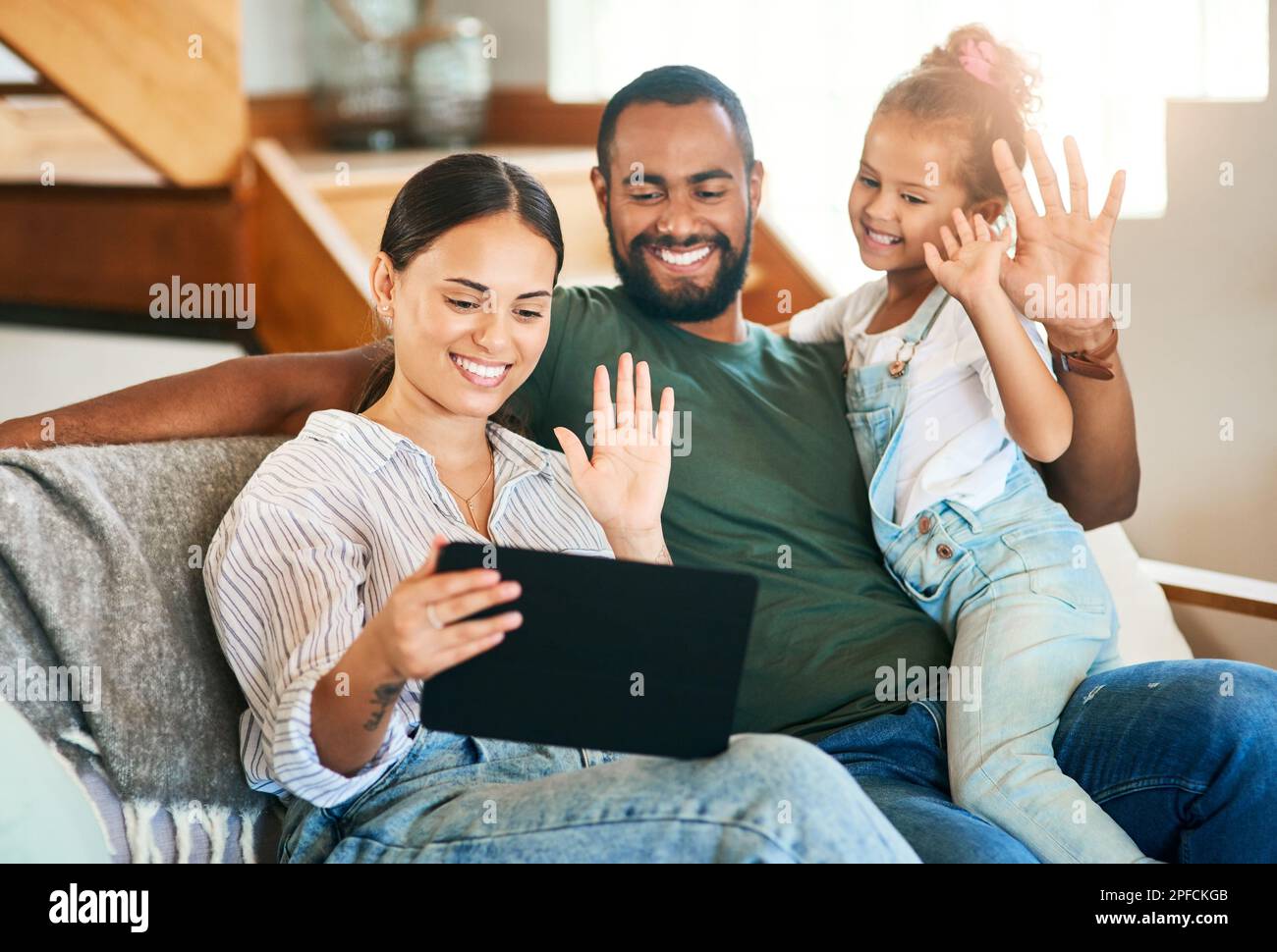 Ciao a tutti. una famiglia felice che effettua una videochiamata su un tablet digitale a casa. Foto Stock