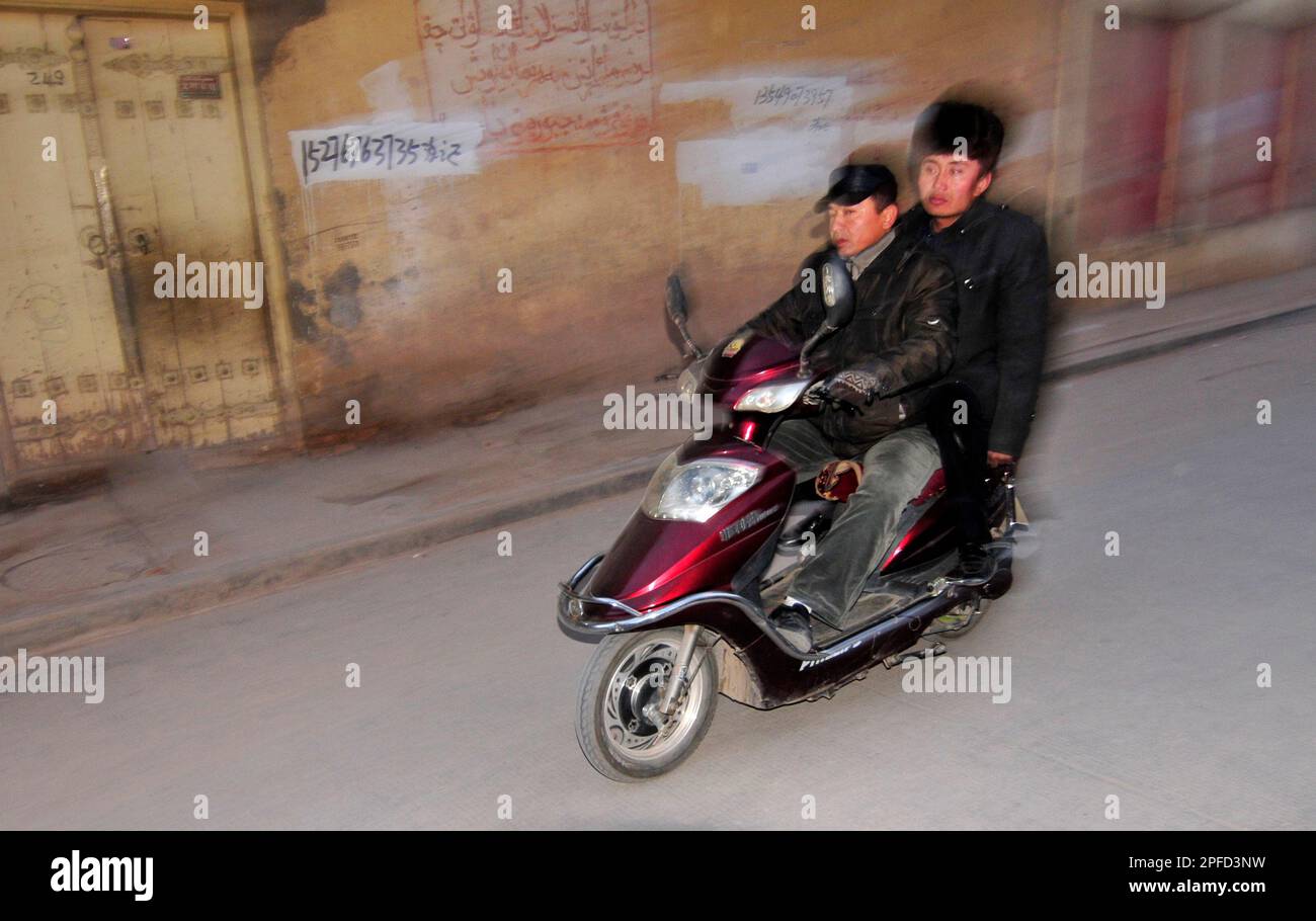 Un uomo Uyghur che guida il suo scooter nella città vecchia di Kashgar, Cina. Foto Stock