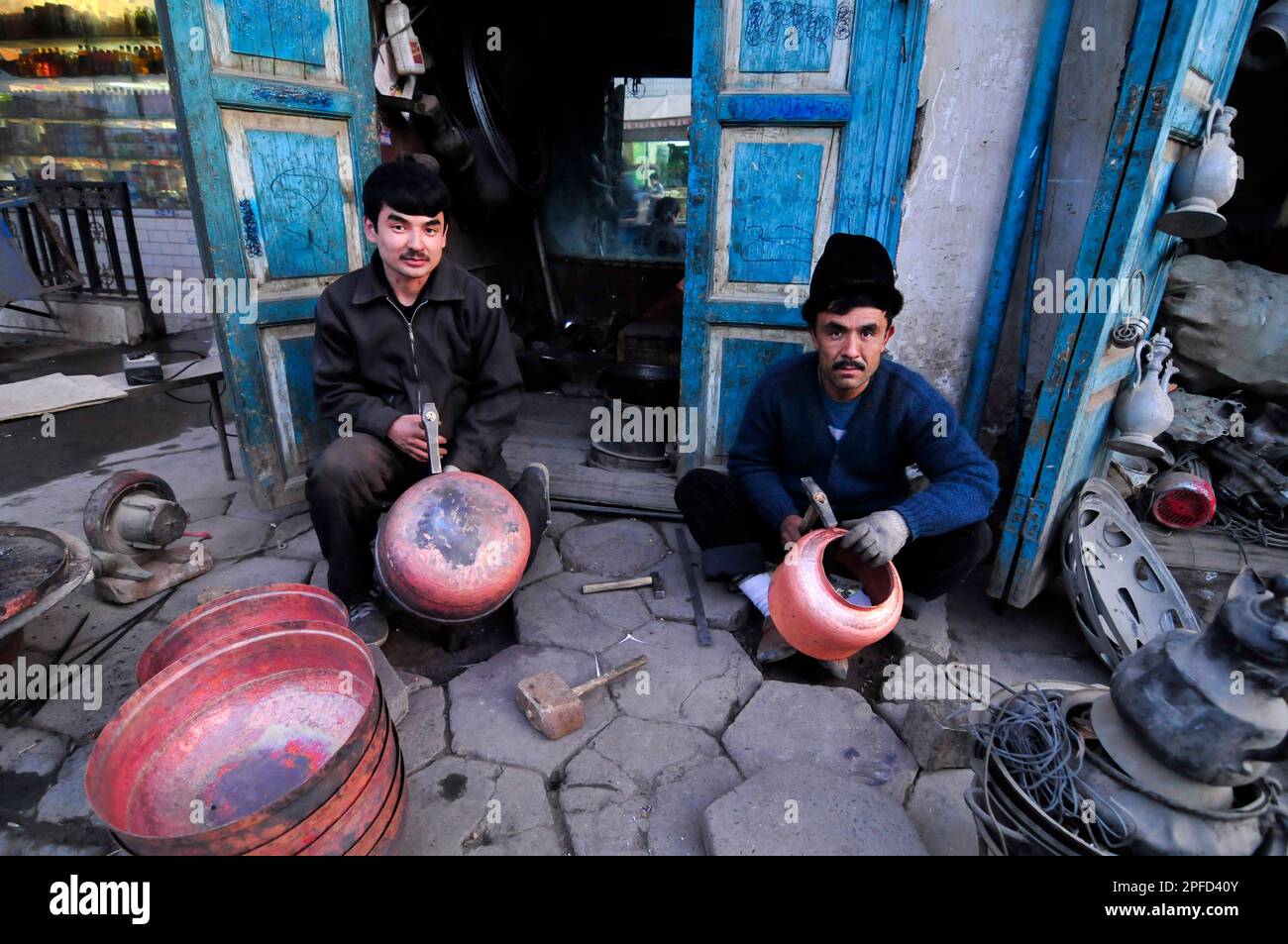 Un fabbro di Uyghur che lavora su pentole tradizionali nella città vecchia di Kashgar, Xinjiang, Cina. Foto Stock