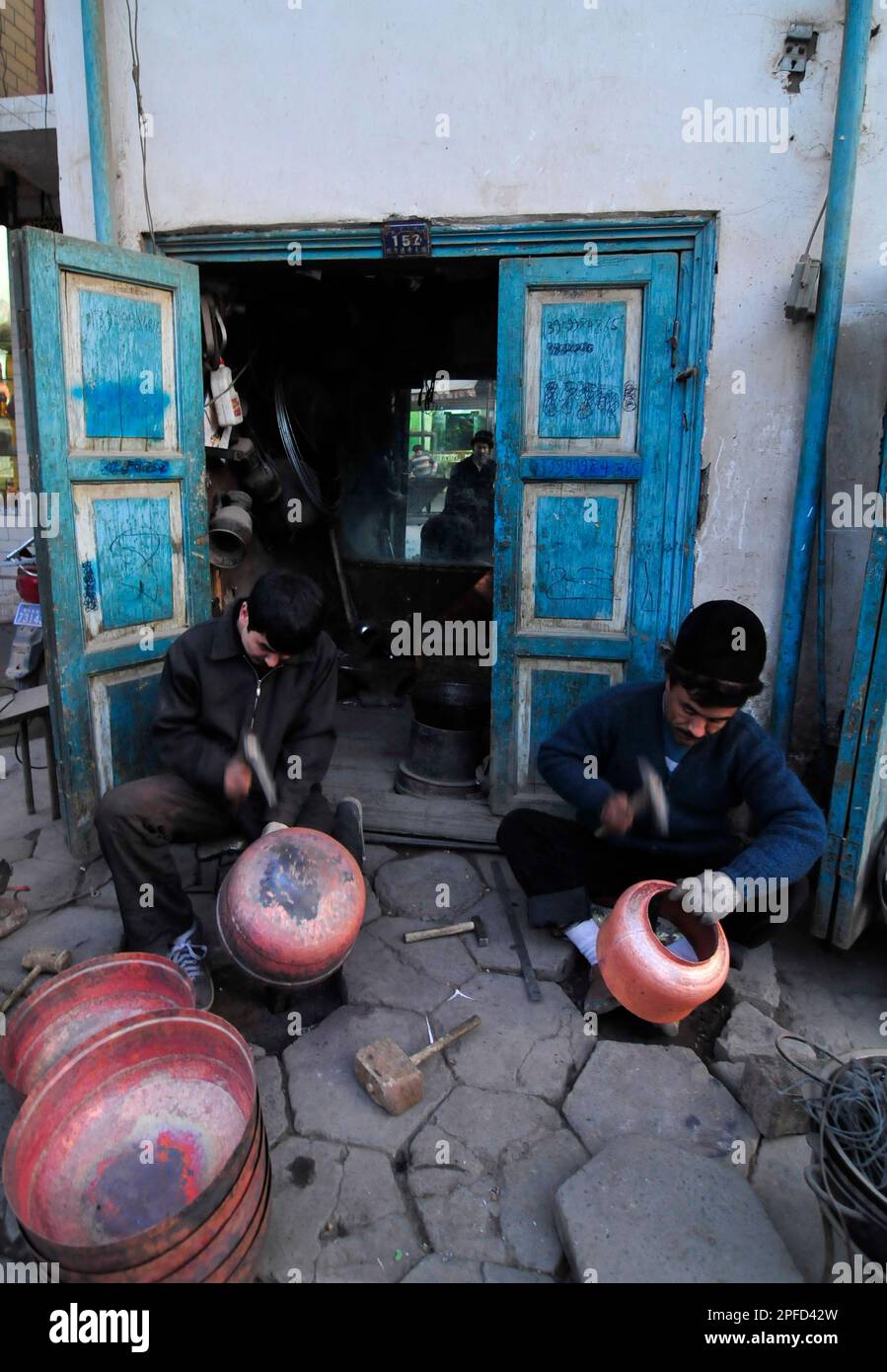 Un fabbro di Uyghur che lavora su pentole tradizionali nella città vecchia di Kashgar, Xinjiang, Cina. Foto Stock