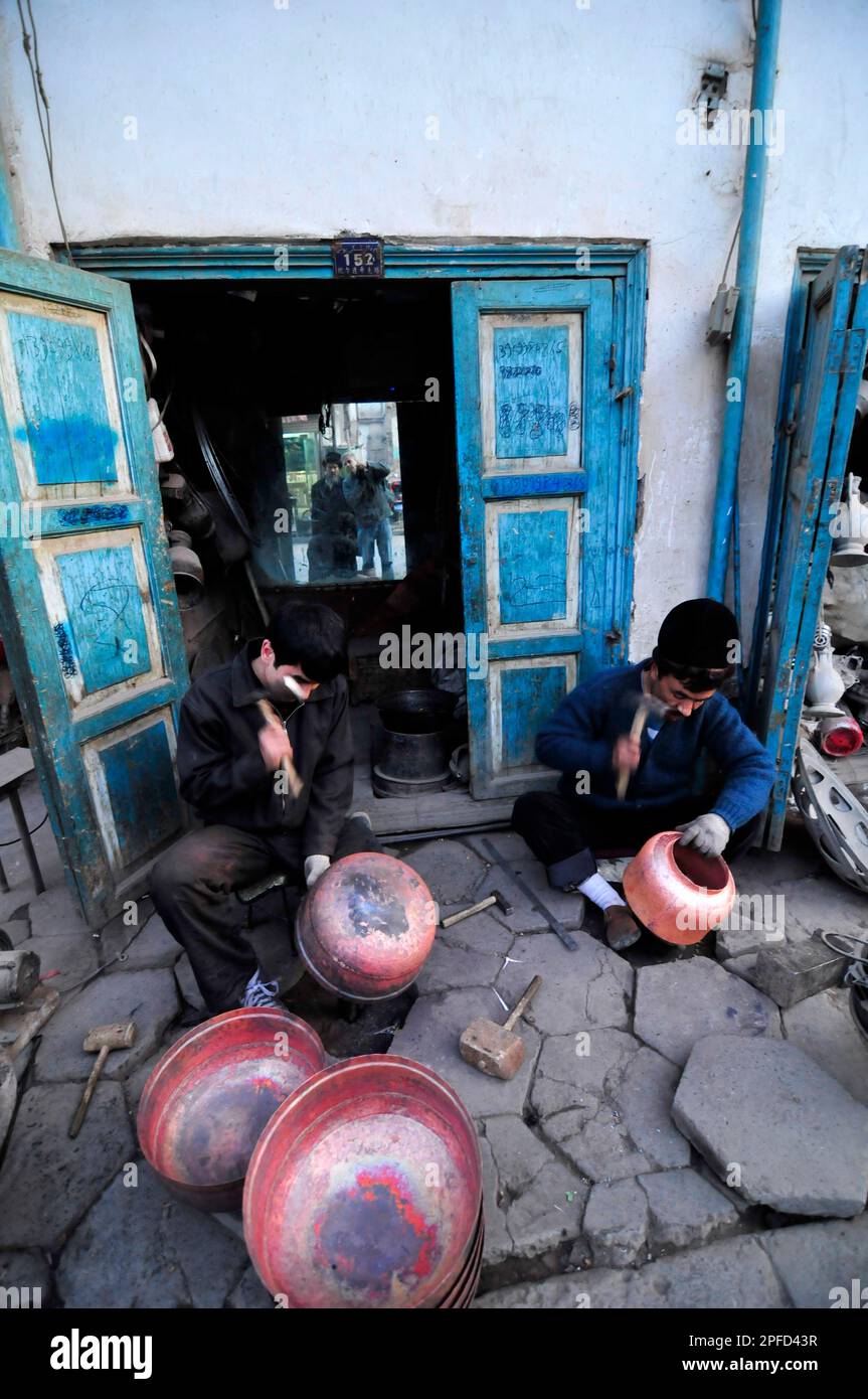 Un fabbro di Uyghur che lavora su pentole tradizionali nella città vecchia di Kashgar, Xinjiang, Cina. Foto Stock