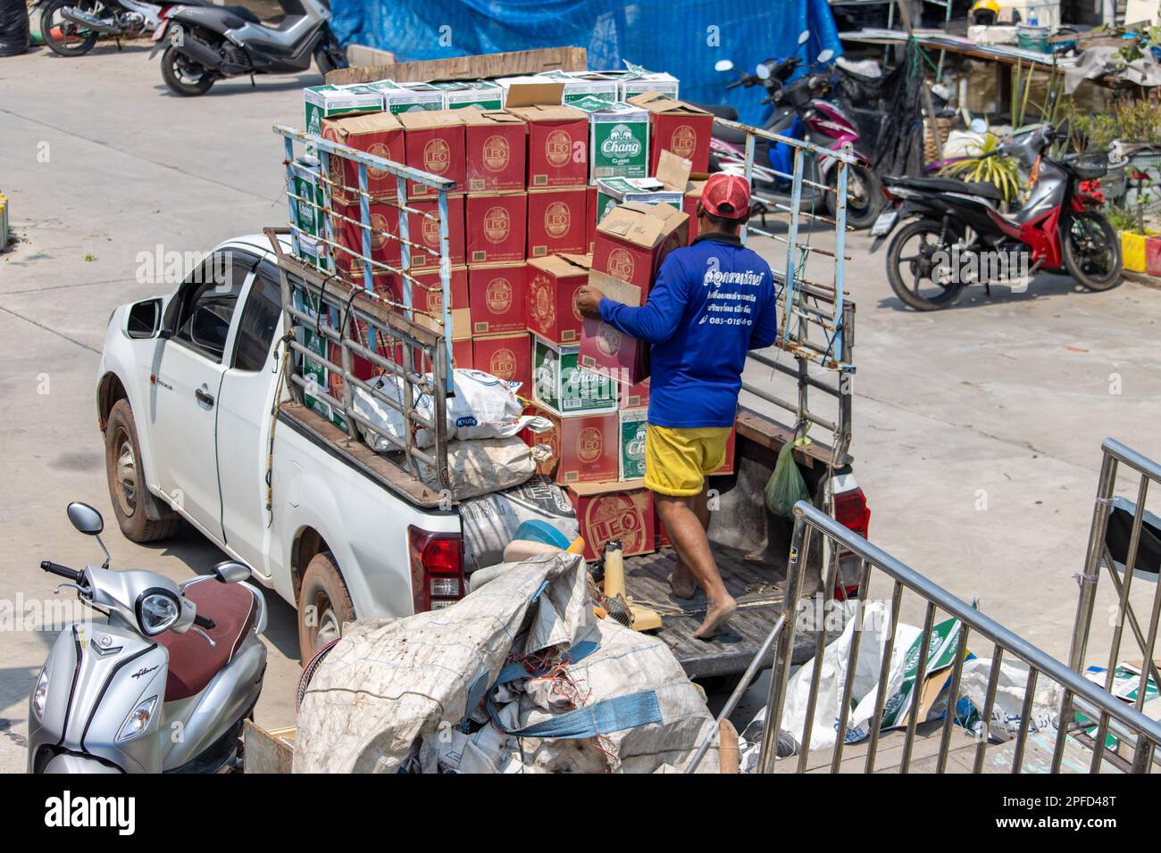 BANGKOK, THAILANDIA, 23 2023 FEBBRAIO, Un uomo a piedi nudi carica i cartoni di birra in un camion pick-up Foto Stock