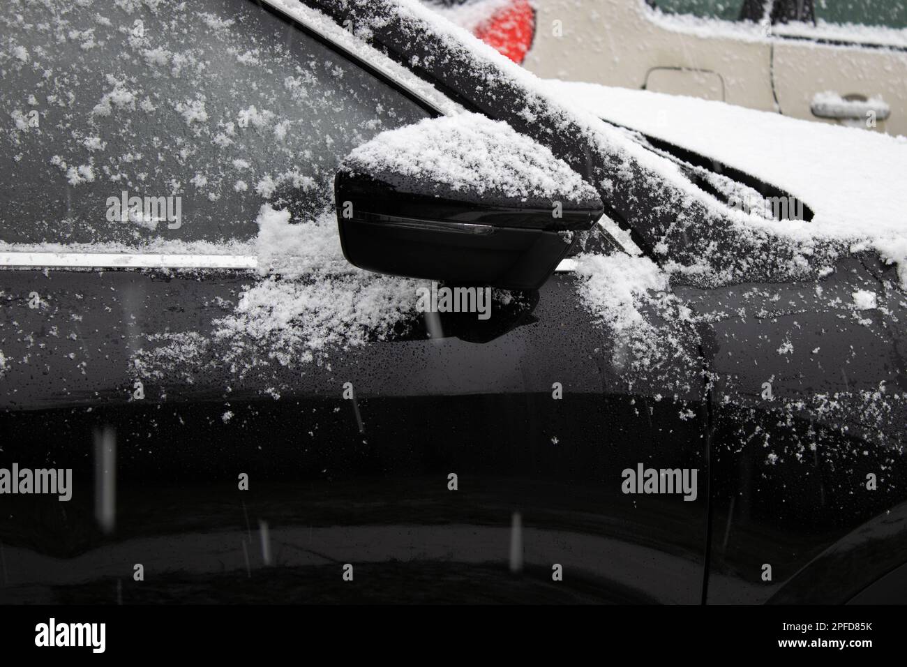 Primo piano di neve su uno specchietto retrovisore nero per auto Foto Stock