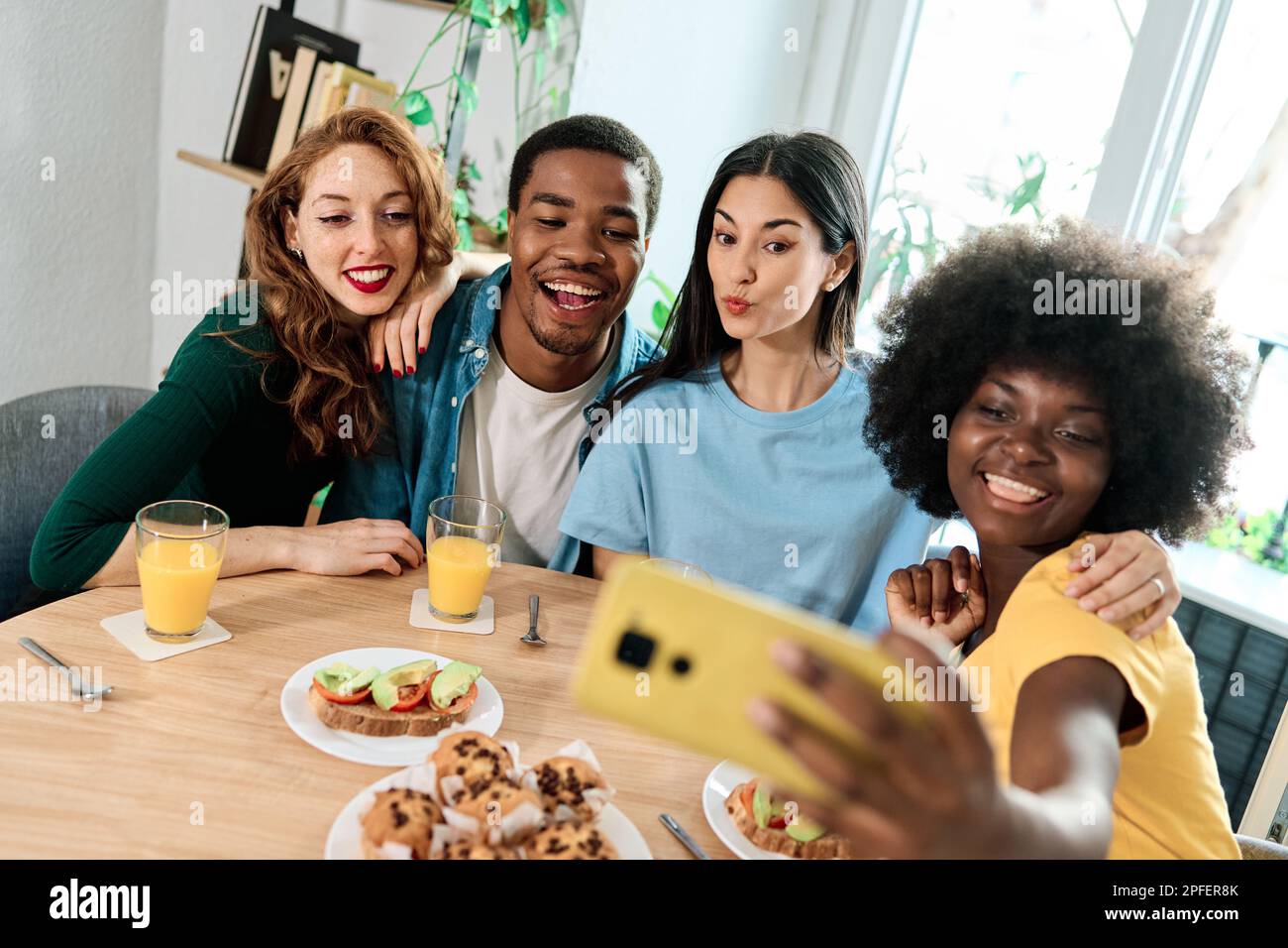 Gruppo di amici multietnici che prendono un selfie in casa Foto Stock