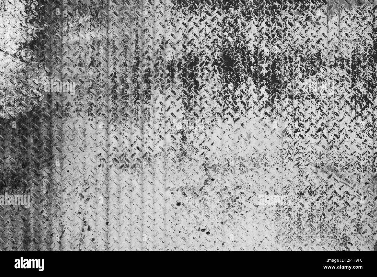 Vecchia parete in metallo con disegno a disco diamantato, pavimentazione industriale. Foto di sfondo in bianco e nero Foto Stock