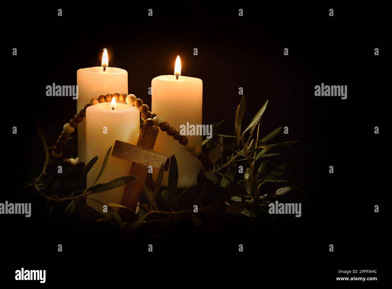 Sfondo religioso pasquale con tre candele che illuminano la croce cristiana e rami di ulivo intorno al crepuscolo. Vista frontale. Foto Stock