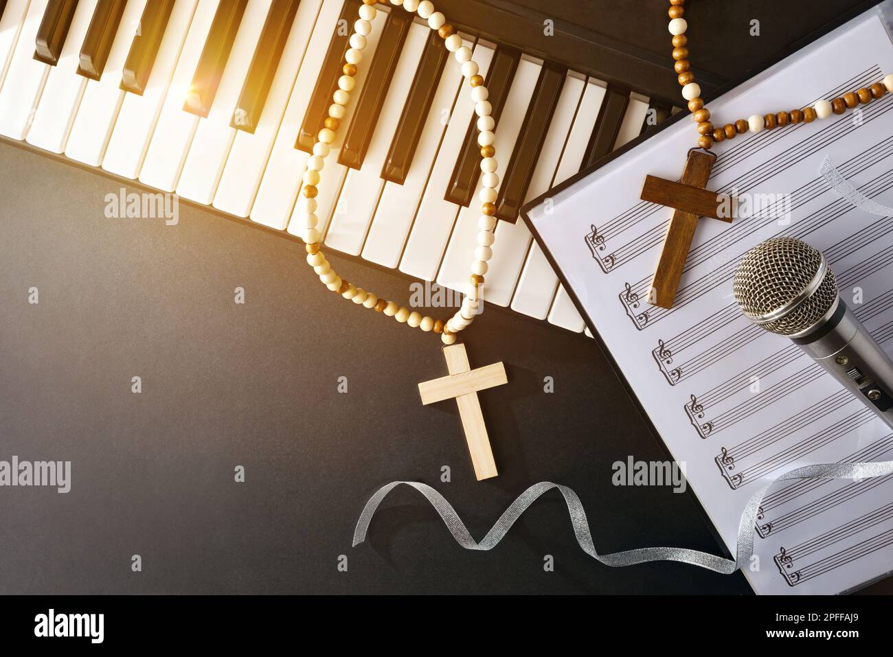 Musica religiosa con pianoforte e microfono su cartella spartiti su un tavolo nero con croci e scintilla dorata. Vista dall'alto. Foto Stock