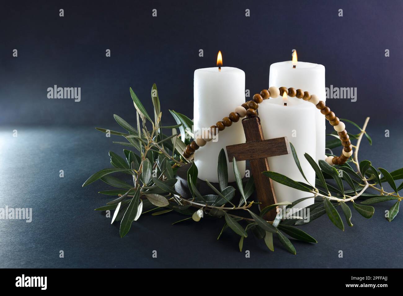Pasqua sfondo religioso con tre candele brucianti croce cristiana e rami di ulivo intorno. Vista frontale. Foto Stock