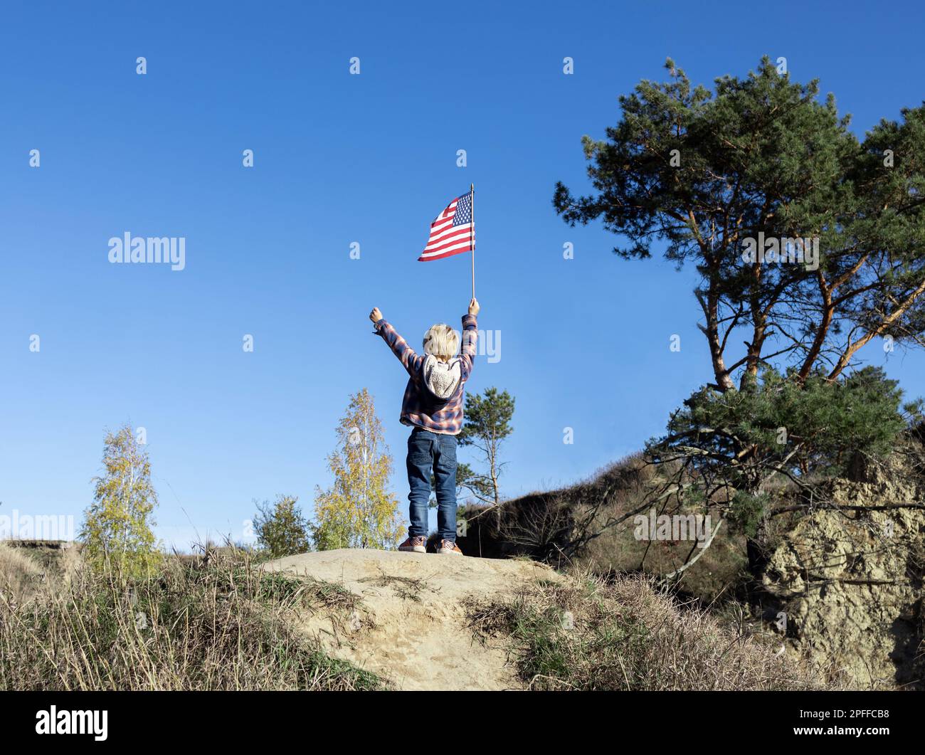 bandiera americana in mano di un bambino irriconoscibile nel parco contro il cielo blu. Simbolo nazionale di libertà e indipendenza degli Stati Uniti di Foto Stock