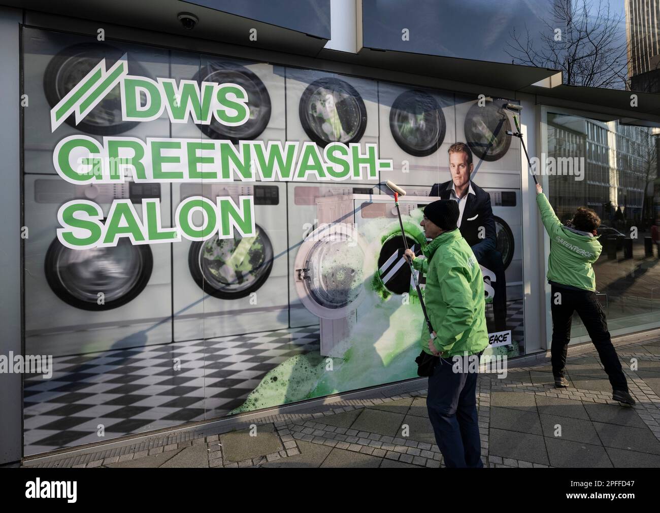 16 marzo 2023, Hesse, Francoforte sul meno: Gli attivisti di Greenpeace coprono la facciata in vetro della controllata Deutsche Bank DWS di Francoforte con immagini di una "lavanderia automatica". Con questo, gli attivisti vogliono protestare contro la politica di sostenibilità di DWS e i bonus per il CEO Stefan Hoops (a destra sul poster). Foto: Boris Roessler/dpa Foto Stock