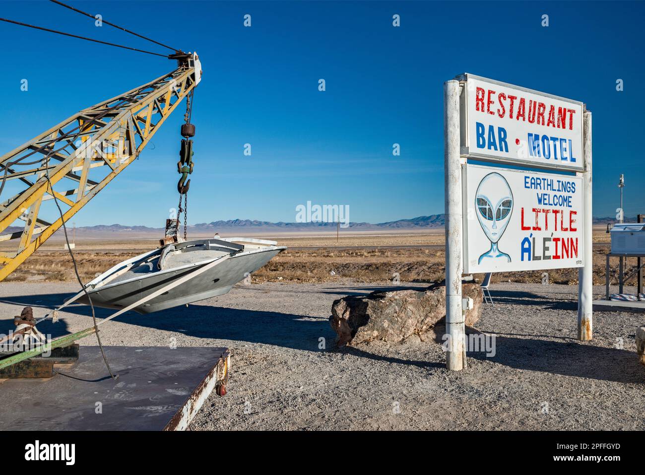 Si è schiantato UFO, appeso al braccio di un carro attrezzi, installazione locale d'arte, segno piccolo A’le’Inn motel, Extraterrestre Hwy NV-375, a Rachel, Grande Bacino Nevada Foto Stock