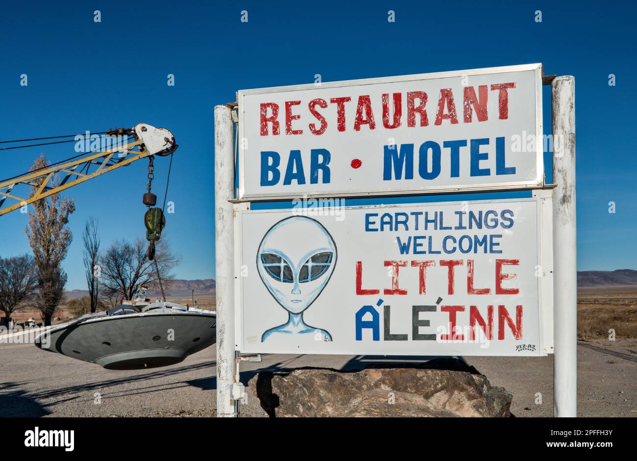 Si è schiantato UFO, appeso al braccio di un carro attrezzi, installazione locale d'arte, segno piccolo A’le’Inn motel, Extraterrestre Hwy NV-375, a Rachel, Grande Bacino Nevada Foto Stock
