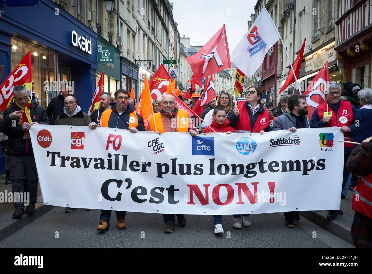 Una manifestazione a Bayeux, Francia contro l'aumento dell'età pensionabile a 64 anni. Il banner si traduce come "lavorare più a lungo - NO!" Foto Stock