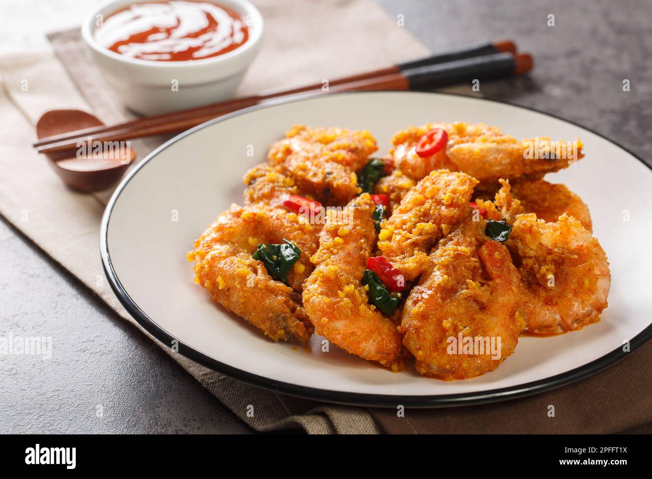 Gamberi asiatici mescolano fritti con tuorli d'uovo salati, foglie di curry e peperoncino primo piano in un piatto sul tavolo. Orizzontale Foto Stock