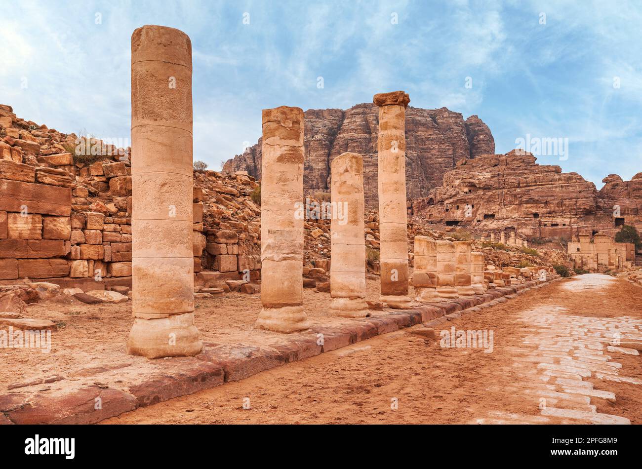 Colonne di pietra rossa rimane in strada colonnaded a Petra, Giordania, montagne rocciose con fori grotta di sfondo abitazioni Foto Stock