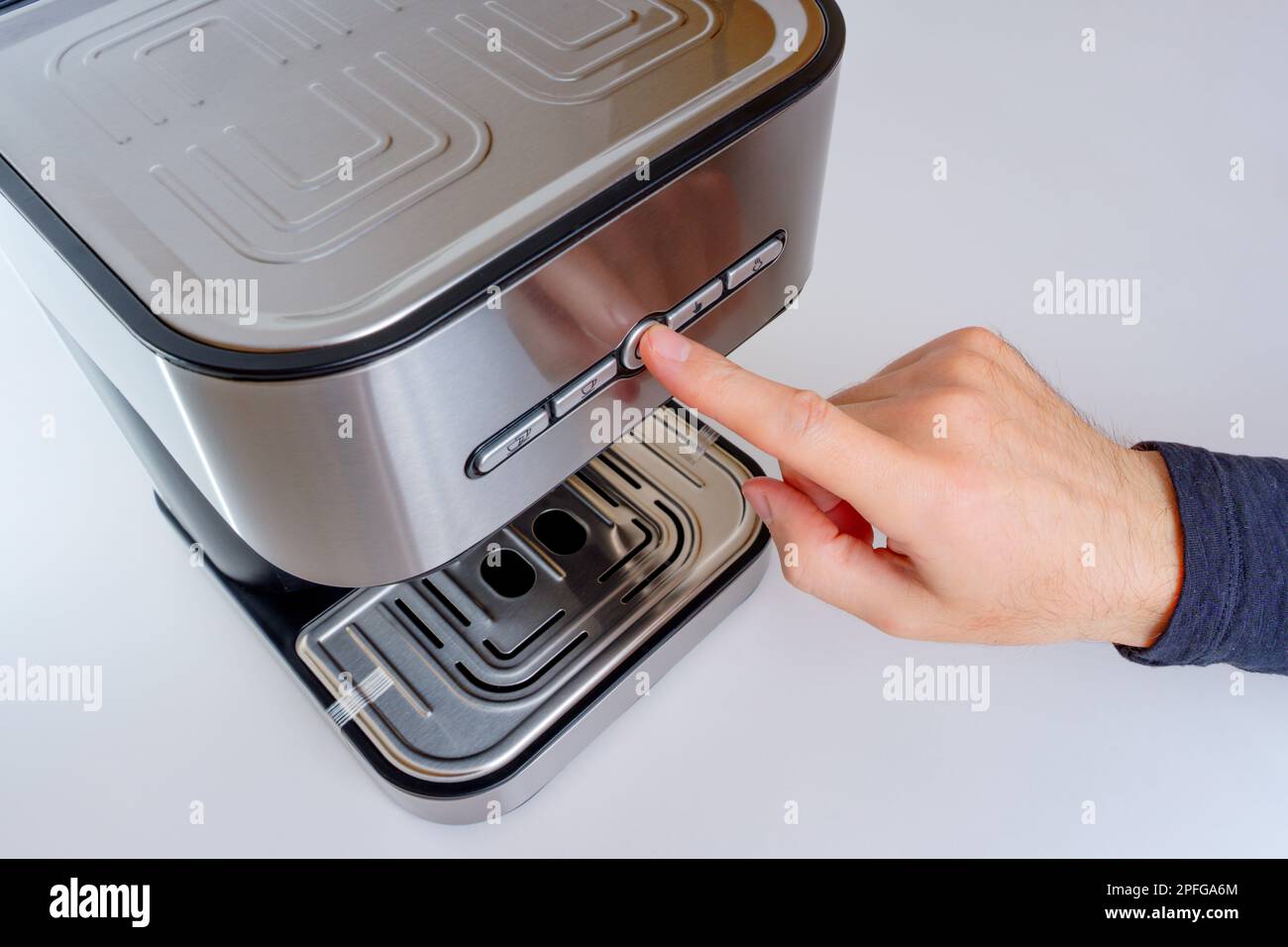 Primo piano di una mano premendo il pulsante START di una nuovissima macchina per caffè espresso. Foto Stock