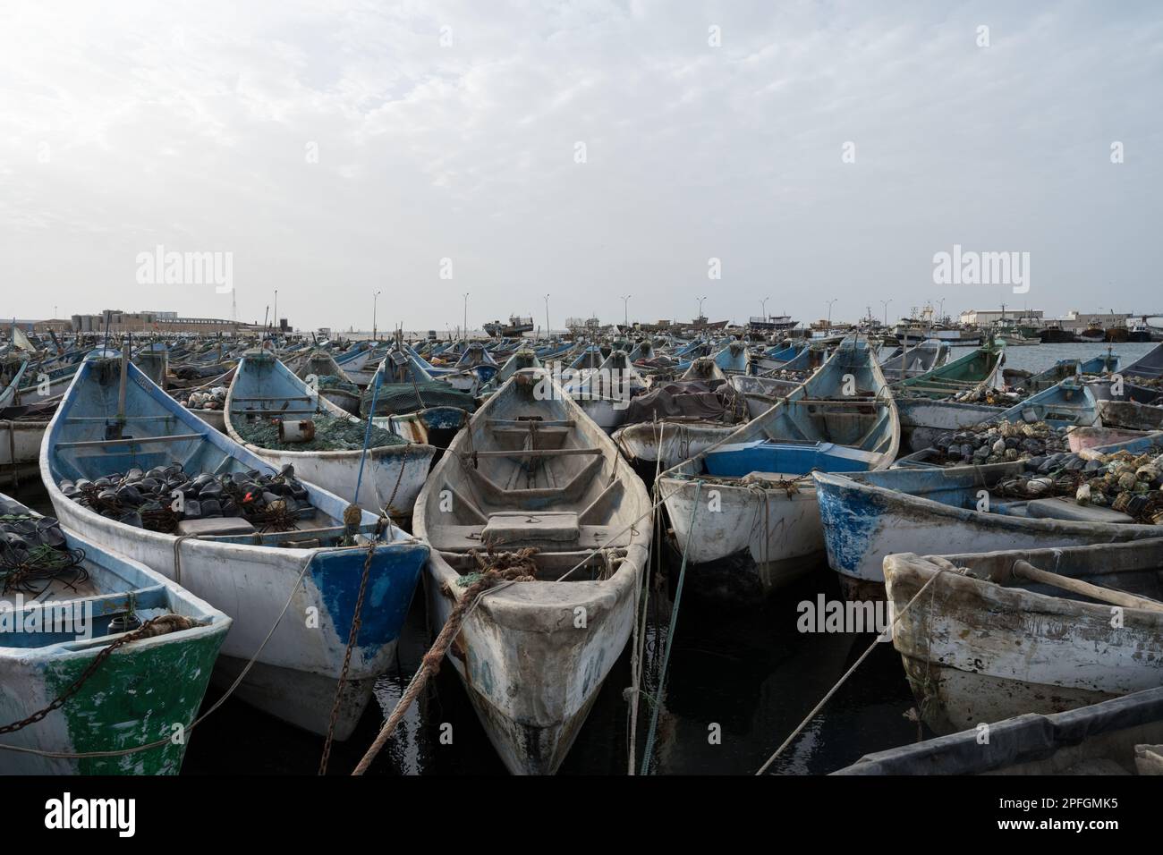 Un gruppo di vivaci barche da pesca blu e bianche a Nouadhibou, Mauritania, che catturano lo stile di vita e la tradizione marinara di questo villaggio costiero di pescatori Foto Stock
