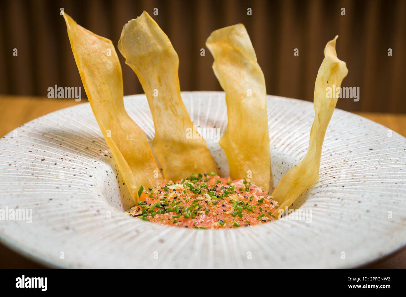 CIBO PERUVIANO. Ceviche di salmone speziato con erba cipollina e lime su un piatto bianco servito con spicchi di patate dolci fritte Foto Stock