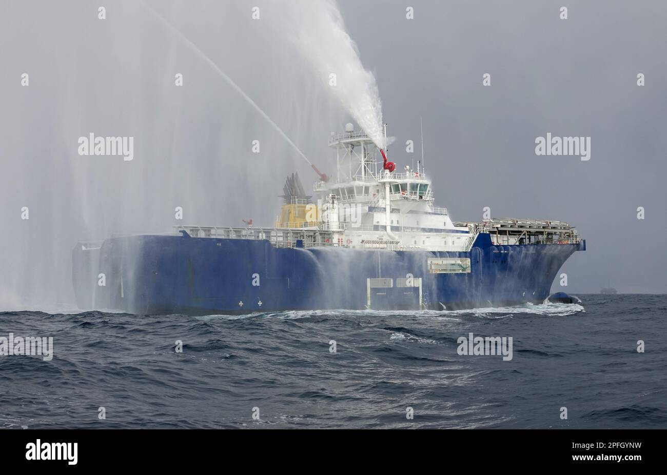 Rimorchiatore che mostra lo scarico dell'acqua. Un piroscafo di salvataggio che getta il ruscello d'acqua all'aperto. La barca di tubo di fuoco sta spruzzando acqua sul mare per il supportin Foto Stock