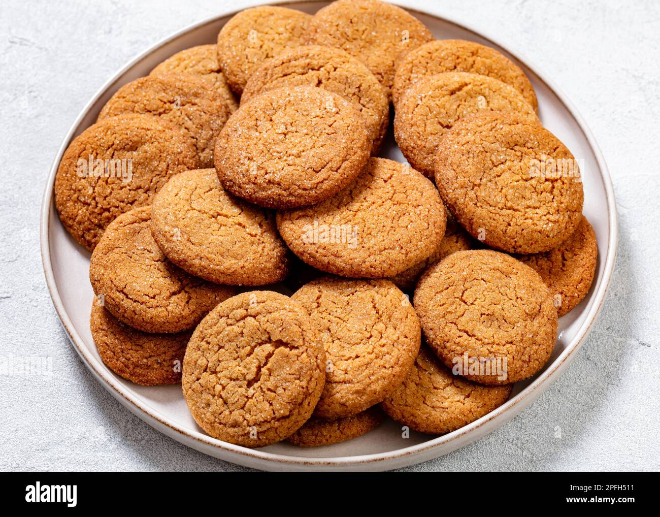 primo piano di dolci e piccanti biscotti allo zenzero su piatto bianco su tavolo bianco Foto Stock