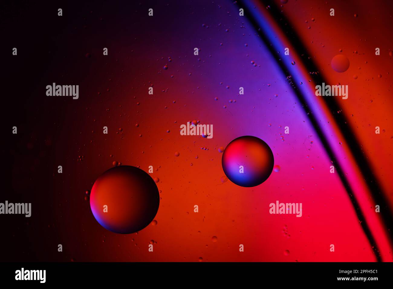 Goccia di olio nell'acqua. Sfondo a colori. Vaso di vetro. Foto Stock