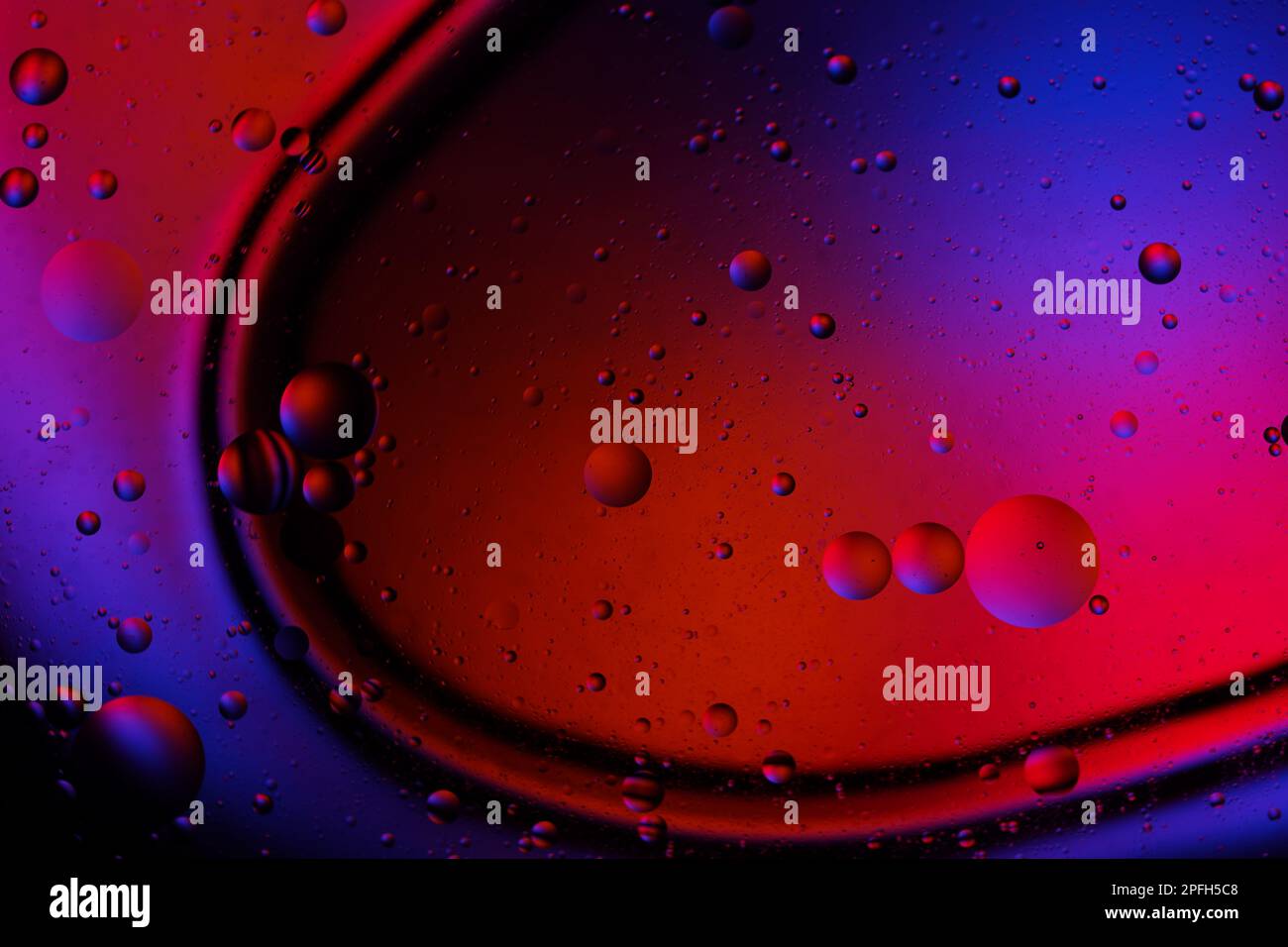 Goccia di olio nell'acqua. Sfondo a colori. Vaso di vetro. Foto Stock