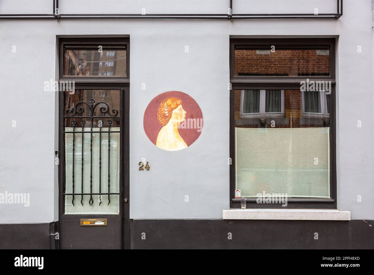 Profilo di una donna dipinta come un macarone su una facciata grigia. Marolles, Bruxelles. Foto Stock