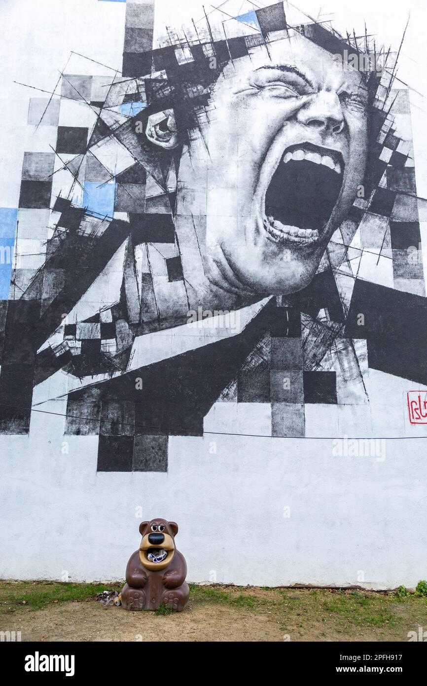 Pittura murale raffigurante una faccia urlante, ai piedi della quale si trova un cestino a forma di orsacchiotto. Bruxelles. Foto Stock